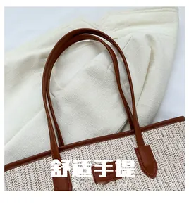 Detail view of woven straw tote bag with brown leather handles and clean texture