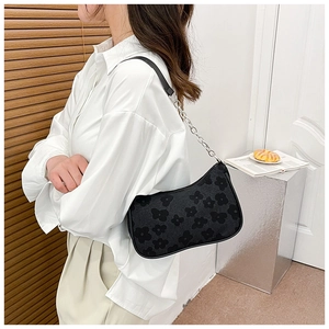 Detail of black underarm bag featuring matte floral texture and silver chain strap