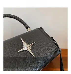 Detail of black pebble leather handbag with silver star stud and woven handle design