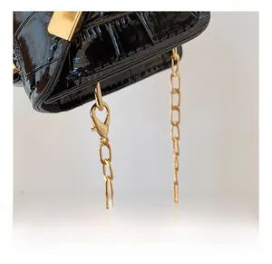 Detail of gold metal hardware and luxury crocodile pattern chain strap on black bag