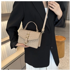 Detail of beige faux crocodile leather handbag with golden heart clasp on black suit
