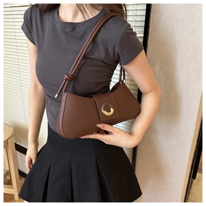 Detail of dark brown faux leather underarm bag featuring a round resin and metal buckle