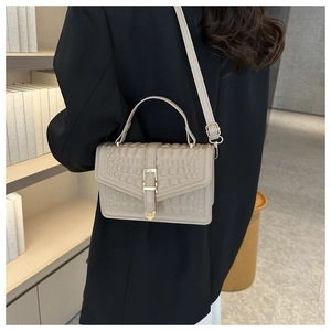 Chic beige crocodile embossed handbag shown on model wearing a sharp black suit