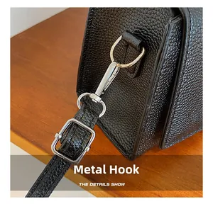 Macro detail of silver hardware hook and pebble leather strap on a black handbag
