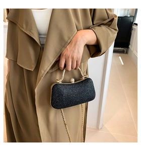 Detail of elegant black glitter evening clutch with gold metal frame and crystal clasp