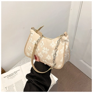 Detail of beige hobo bag with embossed floral texture and silver chain strap