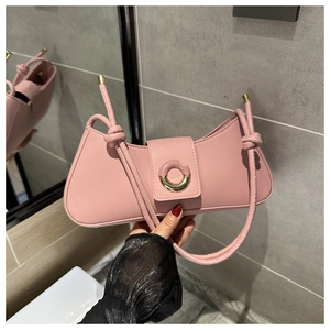 Detail of pink PU leather handbag with a gold round buckle and stylish knot handle