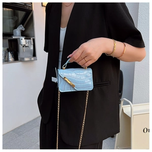 Detail showing light blue crocodile texture mini bag with gold chain strap on model