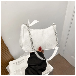 Detail of white pleated bag featuring embossed floral texture and silver chain strap