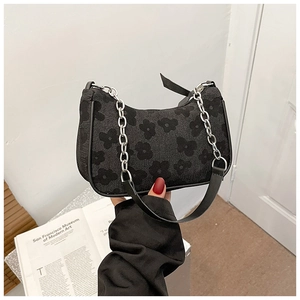 Close-up of black ruched half-moon bag with floral print and stylish silver chain strap
