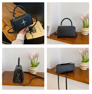 Detail of black pebbled leather crossbody bag with silver star and woven handle
