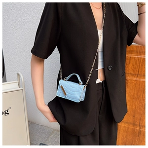 Close-up of light blue croc-effect mini crossbody bag with gold chain on model