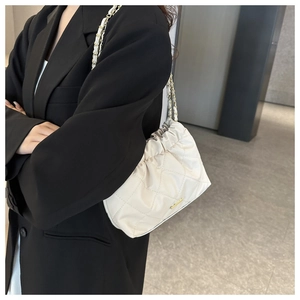 Détail du sac matelassé blanc avec cordon de serrage et bandoulière en chaîne dorée