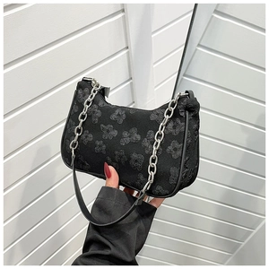 Close-up of black ruched shoulder bag with 3D floral texture and silver metal chain strap