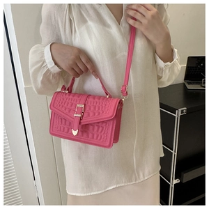 Model wearing rose pink crocodile pattern handbag with gold buckle and thin shoulder strap