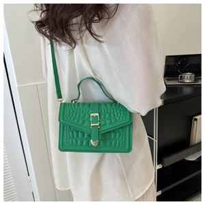 Detail of bright green crocodile pattern bag with gold lock shown in a lifestyle setting