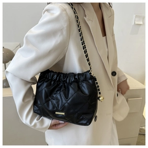 Détail du sac bandoulière matelassé noir avec breloque boule dorée et chaîne