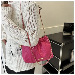 Vue détaillée du sac matelassé fuchsia avec bandoulière chaîne et logo métallique