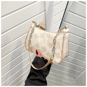 Close-up of beige pleated shoulder bag with yellow floral print and silver chain link
