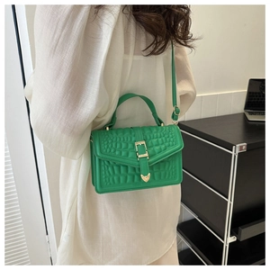 Detailed view of the bright green crocodile embossed leather texture with gold metal buckle