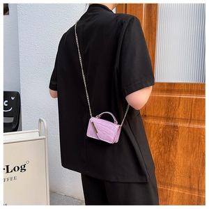 Macro shot of purple crocodile embossed mini chain bag worn on shoulder by model
