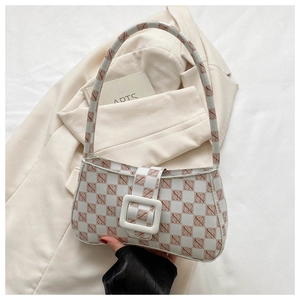 Detail of vintage cream monogram underarm bag with large white resin buckle on beige fabric