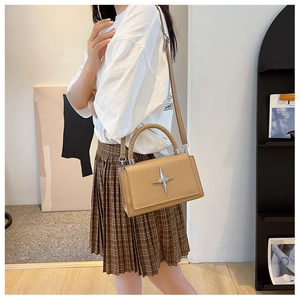 Detail of brown litchi pattern leather square bag with silver star and woven handle
