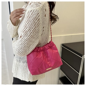 Detail of fuchsia quilted crossbody bag with gold chain and ruching texture