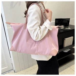Pink waterproof nylon tote bag with leather handles shown in a side-view lifestyle shot