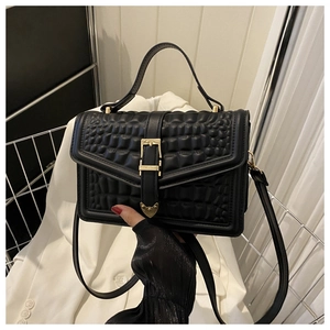 Detail shot of black handbag featuring embossed round texture and gold buckle hardware