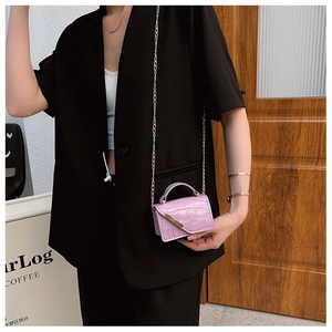Detail of bright pink crocodile embossed mini bag with gold chain and metal buckle