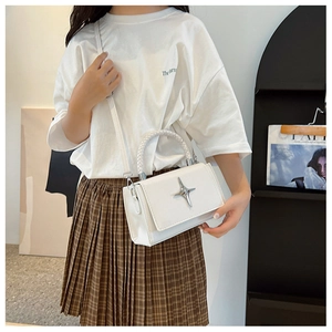 Detail of white PU leather crossbody bag featuring a silver star buckle and textured finish