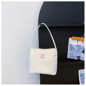 Detailed shot of white nylon shoulder bag featuring pink muen and ebony embroidery