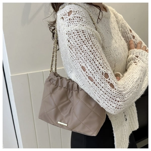 Gros plan du sac seau matelassé kaki avec bandoulière chaîne et texture moelleuse