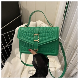 Detail of bright green crocodile embossed handbag with gold buckle and top handle