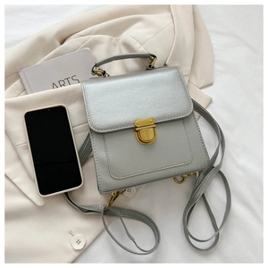 Detail of silver metallic dual-use backpack and handbag with gold vintage lock