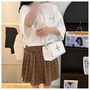 Detail view of white crossbody bag with silver star buckle and woven handle grip