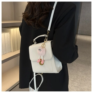 Detailed back view of a white box-style crossbody bag with a cute pink plush toy pendant