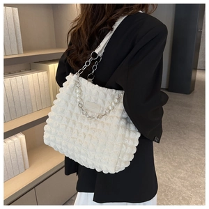 Detail of white bubble textured tote bag with pearl chain strap and clover charm