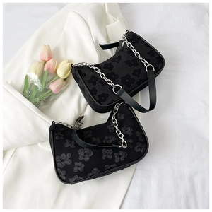 Detail of floral texture black shoulder bags with silver chains on a white blazer