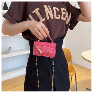 Detail of rose pink crocodile embossed mini bag with gold chain strap on model