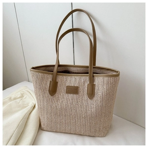 Close-up of large straw tote bag featuring V-shaped weave and brown PU leather handles
