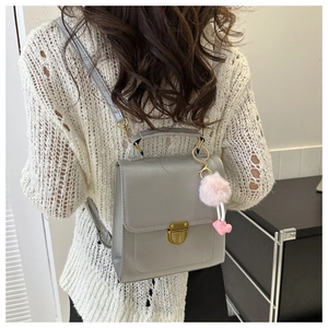 Detailed view of grey faux leather backpack with gold buckle and pink plush heart charm