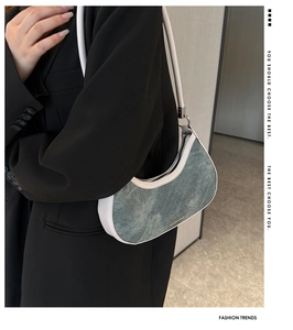 Detail of denim and leather crescent underarm bag worn with a black blazer jacket