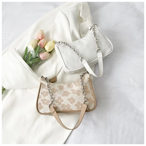 Detail of floral printed and jacquard textured underarm bags with metal chain straps