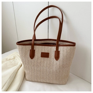 Detail of woven straw texture and premium brown leather trim on the large summer tote bag