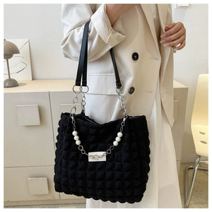 Détail du sac cabas matelassé noir avec chaîne en perles et breloques de fleurs