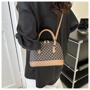 Close-up of a dark brown monogram shell bag showing golden dual zippers and handles