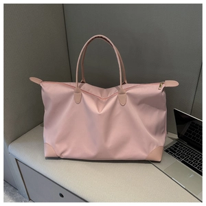 Pink waterproof nylon tote bag next to a laptop showing its large capacity and style