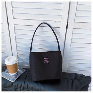 Detail of black nylon tote bag with pink embroidered lettering against a white background